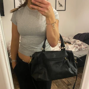Skin väska  - Fin svart skinnhandväska med både Axelband och ”hand” band💕 Väskan har guld detaljer med mycket fickor💕//ha en bra dag 
