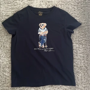 Polo Ralph Lauren T-shirt  - En snygg PoloBear tröja från polo ralph lauren. Det är storlek S. Kragen på t-shirten sitter lite löst. Personen på bilden är 180 och väger 65kg. Priset är ej huggit i sten. Skicka ett meddelande om du undrar något.