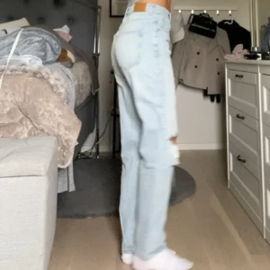 Ljusa jeans med slitningar - Säljer ett par ljusa jeans med coola slitningar på knäna. De har en straight passform och är högmidjade, vilket ger en snygg och bekväm look. Perfekta för en avslappnad stil! Säljer pga tycker de är för korta för mig som är 170 cm