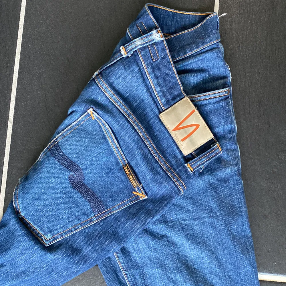 Säljer ett par snygga blå jeans från Nudie Jeans. De har en klassisk femficksdesign med orange sömmar och en bekväm passform. Jeansen är i bra skick. De har en knappgylf och är tillverkade i slitstarkt denim. Nypris är 1600kr. Jeans & Byxor.