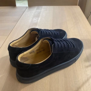 Blåa mocka sneakers  - Säljer ett par stilrena blåa sneakers i mocka från Myrqvist. De har en klassisk design med snörning och en bekväm passform. Skorna är i storlek herr 45 och är i mycket gott skick. priset är inte hugget i sten så kom gärna me förslag! Låda medföljdes