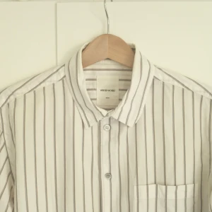 Vit randig skjorta från Wood Wood - Säljer en stilren vit skjorta med ränder från Wood Wood i använt men fint skick. Kan användas av såväl killar som tjejer. Nypris 1800kr. Herrmodell M men snarare small. Fortfarande mycket fin i färgen, men svag gulnad kan ses vid krage och armhåla