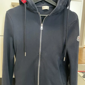 Moncler zip hoodie  - Blå moncler zip hoodie i str xs som är i bra skick ser ganska ny ut men har använts några gånger. Priset är inte hugget i stenen