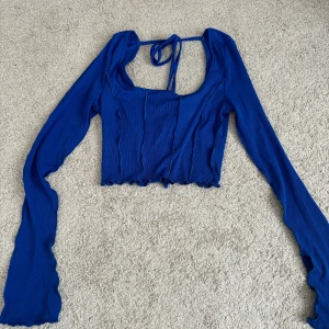 Festtopp  - Snygg blå festtopp med knytning på baksidan i storlek xs. Som ny.