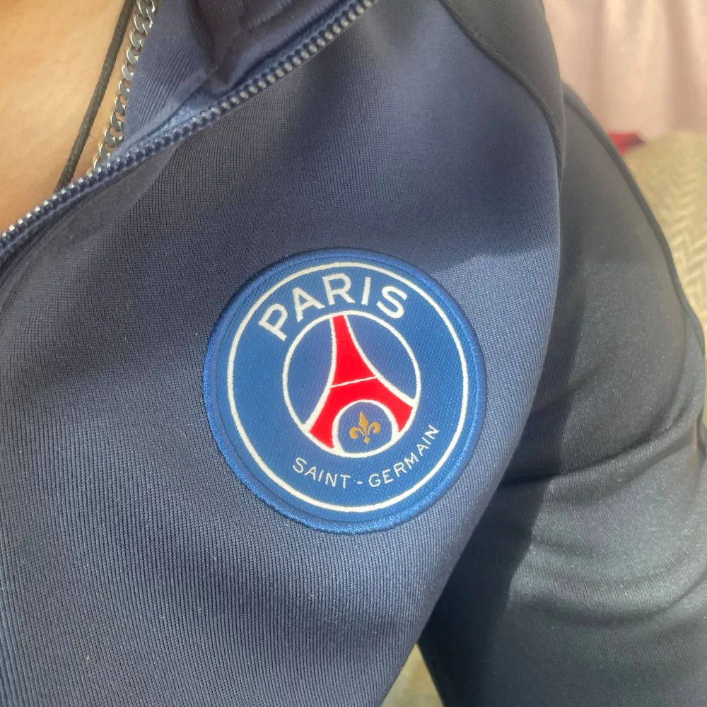 Säljer en snygg mörkblå träningsjacka från Nike med PSG-logga på bröstet. Jackan har en dragkedja framtill och långa ärmar. Assnygg och i perfekt skick, inga defekter. Ganska svår att få tag på idag. . Jackor.