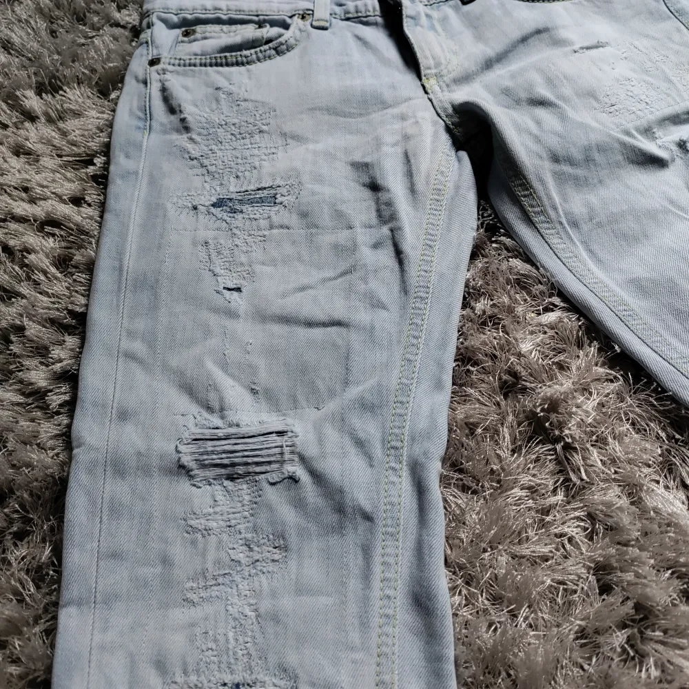 Säljer ett par ljusblå ripped jeans från Dondup. I storlek W27. De har en snygg naturlig slitning på framsidan. Jeansen är i en straight passform. Perfekta för både vardag och fest! Skick 9/10!. Jeans & Byxor.