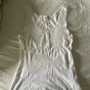 Linne h&m - En vit tanktop med spetsdetaljer vid halsringningen. Storlek m