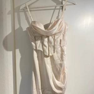 Princess polly klänning - Princess polly klänning, cremefärgad, med strass o hög slits. Ena strassen har fästet släppt men är lätt o fixa med nål och tråd. Endast använd en gång. 