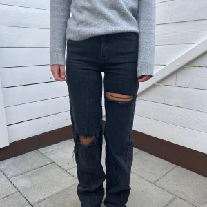Svarta jeans - Svarta högmidjade jeans med hål på. 