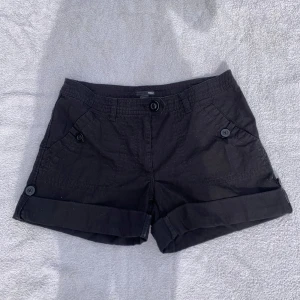 Shorts - Svarta enkla shorts från H&M köpta second hand. Fram och bakfickor, coola knappar. Går att vika ner ca 8 cm till. Storlek 40, passar M. Midjemått: 41 cm. Bra skick🖤