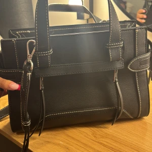 zara väska svart - heej, tänkte sälja denna snygga väska från Zara den har fina detaljer och är väldigt användbar, jag har ej använt den då jag har andra väskor som kommit till nytta. Köpte denna väska utomlands för 45 € vilket motsvarar 500 kr, skriv vid intressen!