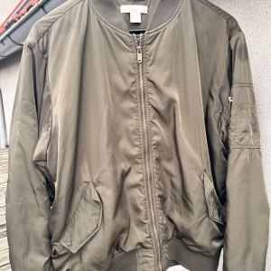 Tunn militärgrön bomberjacka från H&M! - Tunn militärgrön bomberjacka med fickor fram, dragkedja och dom klassiska detaljerna i storlek L från H&M. Jackan är välanvänd men hel och ren. Det är en unisexmodell och motsvarar storlek S i herr. 