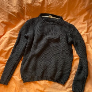 Svart stickad tröja från American Vintage - Säljer en stilren svart stickad tröja från American Vintage. Tröjan har en klassisk rund hals och långa ärmar, perfekt för kyligare dagar. Den är mjuk och bekväm, idealisk för både vardag och avslappnade tillfällen.