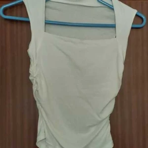 Ärmlös topp i tre färger - Säljer en stilren ärmlös topp i tre olika färger: vit, röd och svart. Toppen har en fyrkantig halsringning och rynkade sidor som ger en smickrande passform. Perfekt för att mixa och matcha med olika outfits. 