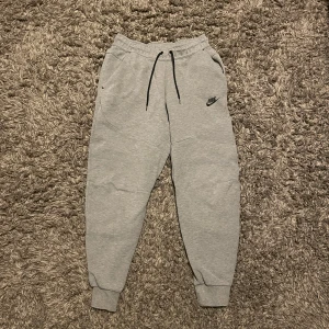 Grå Nike tech byxor - Säljer mina gamla Nike tech byxor för att de inte används. Inget fel på byxorna utan de är bara för små. Nypris är 950kr hör av er vid frågor. 