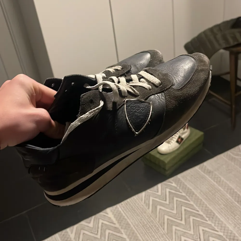 Snygga svarta sneakers med vita snören och detaljer. Skorna har en kombination av skinn och mocka, vilket ger dem en stilren look. Perfekta för en casual stil. Storlek 43 passar mindre. Kengät.