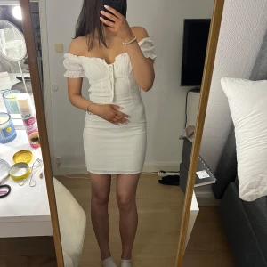 Vit klänning med puffärmar - Charmig vit klänning från Bik Bok med puffiga kortärmar och knytning framtill. Den har en smickrande passform och är perfekt för sommarens varma dagar.