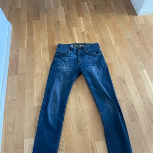 Blå jeansbyxor - Snygga blå jeansbyxor med klassisk femficksdesign och knappgylf. Perfekta för en avslappnad stil med en lätt tvättad look.