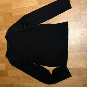 Svart ribbad tröja från Clothes  - Säljer en stilren svart ribbad tröja från Clothes i storlek XS. Tröjan har långa ärmar och en klassisk passform, perfekt för lager-på-lager eller som den är. Ett mångsidigt plagg för garderoben!