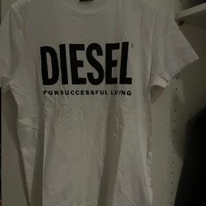 Vit t-shirt från Diesel - Snygg vit t-shirt från Diesel med stort svart tryck på framsidan. Perfekt för en casual look. Tillverkad i mjukt material för extra komfort.