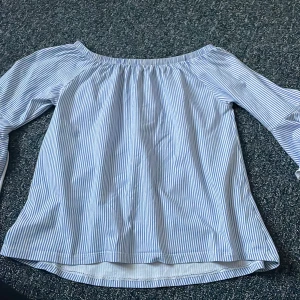 En blå somrig blus  - En blå randig blus med volanger på ärmarna 