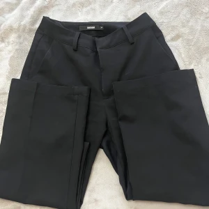Svarta kostymbyxor från BikBok - Snygga svarta kostymbyxor från BikBok med en klassisk design. Byxorna är bootcut samt har hällor för bälte och en diskret dragkedja framtill.