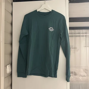 Grön långärmad tröja från Dickies - Säljer en grön långärmad tröja från Dickies med logotyp på bröstet och ryggen. 