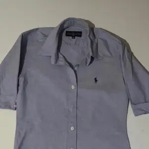 Snygg ljusblå skjorta från Ralph Lauren med klassisk krage och knappar framtill. Skjortan har tre kvarts ärmar och det ikoniska broderade logotypen på bröstet. Storlek M, fint skick inget att anmärka!