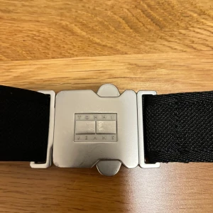 Svart buckle bälte från Tommy Hilfiger - Säljer detta coola clip skärpet från Tommy Jeans som inte används längre. Storleken är justerbar och den är i gott skick. Nypris: 740kr
