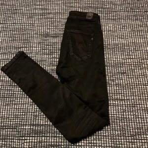 Svarta jeans från Replay - Snygga svarta jeans från Replay med en tight passform. De har klassisk femficksdesign och är tillverkade i ett stretchigt material för extra komfort. Perfekta för en stilren look.