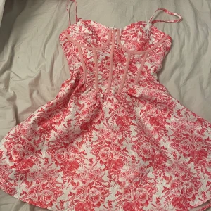 Rosa blommig klänning från Shein - Charmig rosa och vit blommig klänning från Shein med smala axelband och en figurnära passform. Klänningen har en vacker blommig design. Helt oanvänd!
