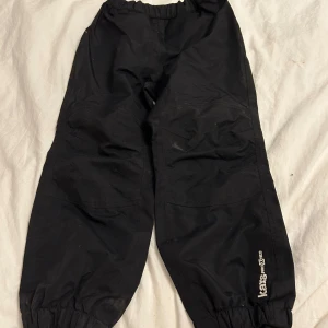 Svarta överdragsbyxor från Kaxs - Säljer ett par svarta överdragsbyxor från Kaxs Proxtec i storlek 122. Byxorna har elastisk midja och reflexdetaljer på baksidan för ökad synlighet. Perfekta för utomhusaktiviteter. De kommer tvättas innan de skickas! ⭐️