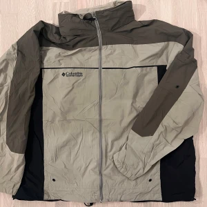 Beige och svart vindjacka från Columbia - Säljer en beige och svart vindjacka från Columbia. Jackan har en dragkedja framtill och är långärmad. Perfekt för blåsiga dagar med sin lätta och funktionella design.