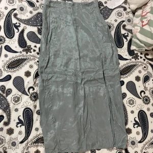  långkjol från H&M med slit - Snygg grå långkjol från H&M i ett glansigt material. Kjolen har en elegant slits på sidan och en bekväm passform. Perfekt för en stilren look.