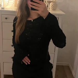 Svart stickad tröja från Weekday - Snygg svart stickad tröja från Weekday med ett as snyggt hålmönster. Tröjan har långa ärmar och en rund halsringning, perfekt för kyligare dagar. En stilren och mångsidig tröja som passar till många olika outfits.