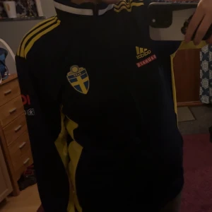 Blå fotbollströja från Adidas (pris kan diskuteras) - Säljer en blå fotbollströja från Adidas med gula detaljer och Sveriges landslagsemblem på bröstet. 