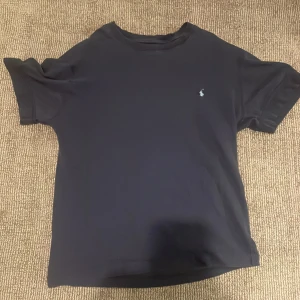 Svart t-shirt från Polo Ralph Lauren - Snygg svart t-shirt från Polo Ralph Lauren med det klassiska broderade logotypen på bröstet. Tillverkad i en skön blandning av bomull och linne, perfekt för en avslappnad stil.