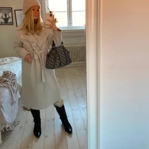 Beige kappa - Snygg beige trenchcoat med knytband i midjan. Perfekt för höst och vår. Långärmad design med klassisk stil. Saknar knytbandet, men är lika snygg öppen.