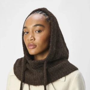Object Milu balaclava - Mysig brun stickad balaklava perfekt för kyliga dagar. Den har en enkel design med ett snöre för justering. Detta är toppen då man kan bestämma om den ska sitta löst eller hårt. Passar utmärkt för höst och vinter. Helt ny, med prislapp kvar