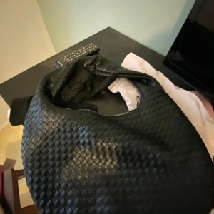 Svart flätad axelväska från Gina tricot - Snygg svart axelväska med flätat mönster från Gina tricot, den e helt ny aldrig andvänd