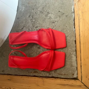Röda sandaler med klack från Mango - Snygga röda sandaler med klack och fyrkantig tå från Mango! De har en elegant remdesign och är perfekta för att lyfta vilken outfit som helst. Den perfekt detaljen!!