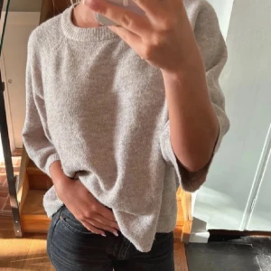 Beige stickad tröja - Mysig beige stickad tröja med trekvartsärm och rund hals. Perfekt för kyligare dagar och enkel att matcha med jeans eller kjol.