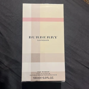 London Eau de Parfum från Burberry *100 ml* (OBS! Bilden visar pris för 30ml) - Elegant parfym från Burberry med en klassisk och stilren design helt oanvänd. Flaskan är klädd i Burberrys ikoniska rutmönster i beige, rött och svart. Perfekt för den som vill ha en tidlös doft med en touch av lyx. Älskarrrr doften men ville köpa något annat för jag har redan det i 30ml. NYPRIS 1250💕💕