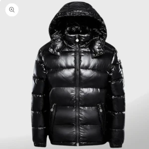 Svart pufferjacka med huva - Snygg svart pufferjacka med glansig yta och praktisk huva. Jackan har dragkedja framtill och två fickor med dragkedjor. Perfekt för kyliga dagar. Pm för frågor 