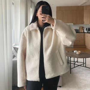 Vit teddyjacka - Mysig vit teddyjacka i oversized passform. Perfekt för höst och vinter med dragkedja framtill och långa ärmar. Jackan är supermjuk och håller dig varm under kyliga dagar. Ett måste för garderoben om du älskar komfort och stil!