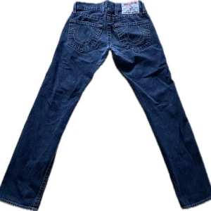 True religion jeans straight fit - Säljer ett par snygga mörkblå jeans med coola broderade detaljer på bakfickorna. De har en klassisk straight passform och är perfekta för både vardag och fest. Jeansen är i bra skick och redo för en ny ägare! Str 28/33 men passar mig som vanligtvis har 30/34