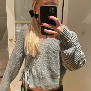 Grå stickad omlottkofta - Säljer en supermysig grå stickad omlottkofta med knytband i midjan