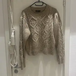 Säljer en supermysig beige stickad tröja från Mango. Den har ett snyggt flätmönster och långa ärmar. Perfekt för höst och vinter, och den är i bra skick. Passar perfekt till jeans eller kjol för en avslappnad look.