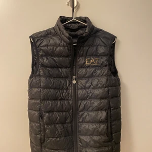 Svart dunväst från Emporio Armani - Snygg svart dunväst från Emporio Armani. Bra skick, inga skador. Storlek M men skulle säga att den passar s/m! Kan diskutera pris! 