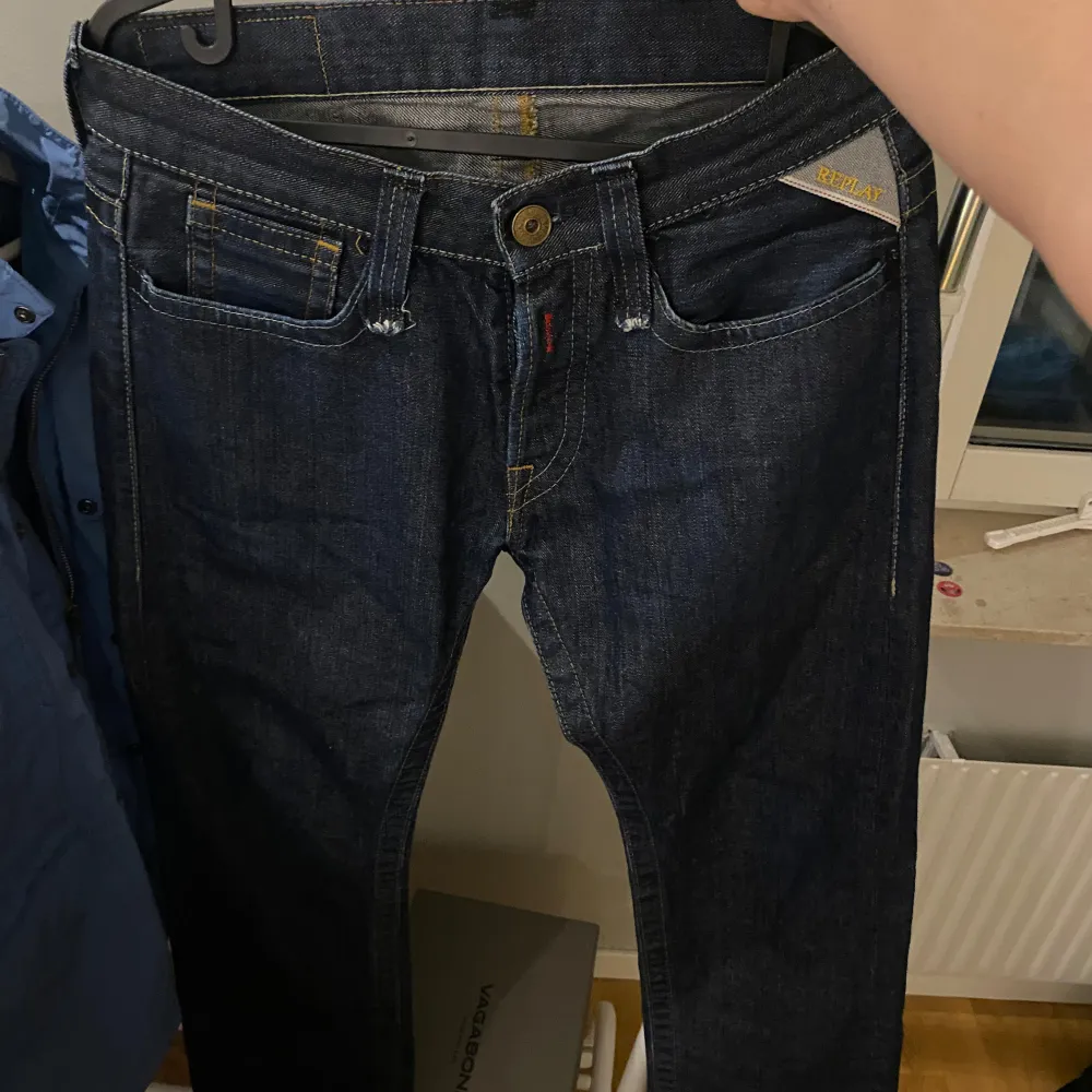 Säljer ett par snygga mörkblå jeans från Replay. De har en klassisk femficksdesign med guldfärgade sömmar och en knappgylf. Perfekta för både vardag och fest! Passar någon runt 175 i längden skulle jag säga. Och i midjan 27.. Jeans & Byxor.